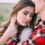 A romantic moment between a couple in a serene outdoor field.