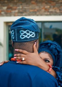Couple embraces warmly wearing traditional Nigerian clothing, capturing love.